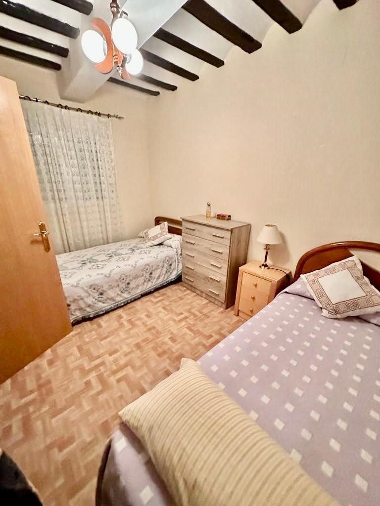 Dormitorio con cama individual amueblado con mueble con baldas cajoneras y  puertas de madera de peral